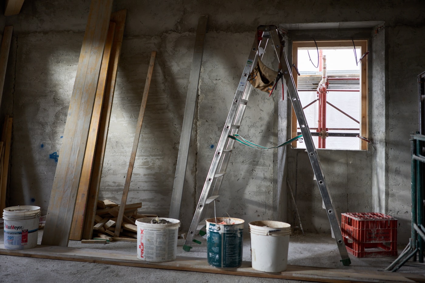 The room mid-renovation with a ladder, paint buckets and bare stripped walls.
